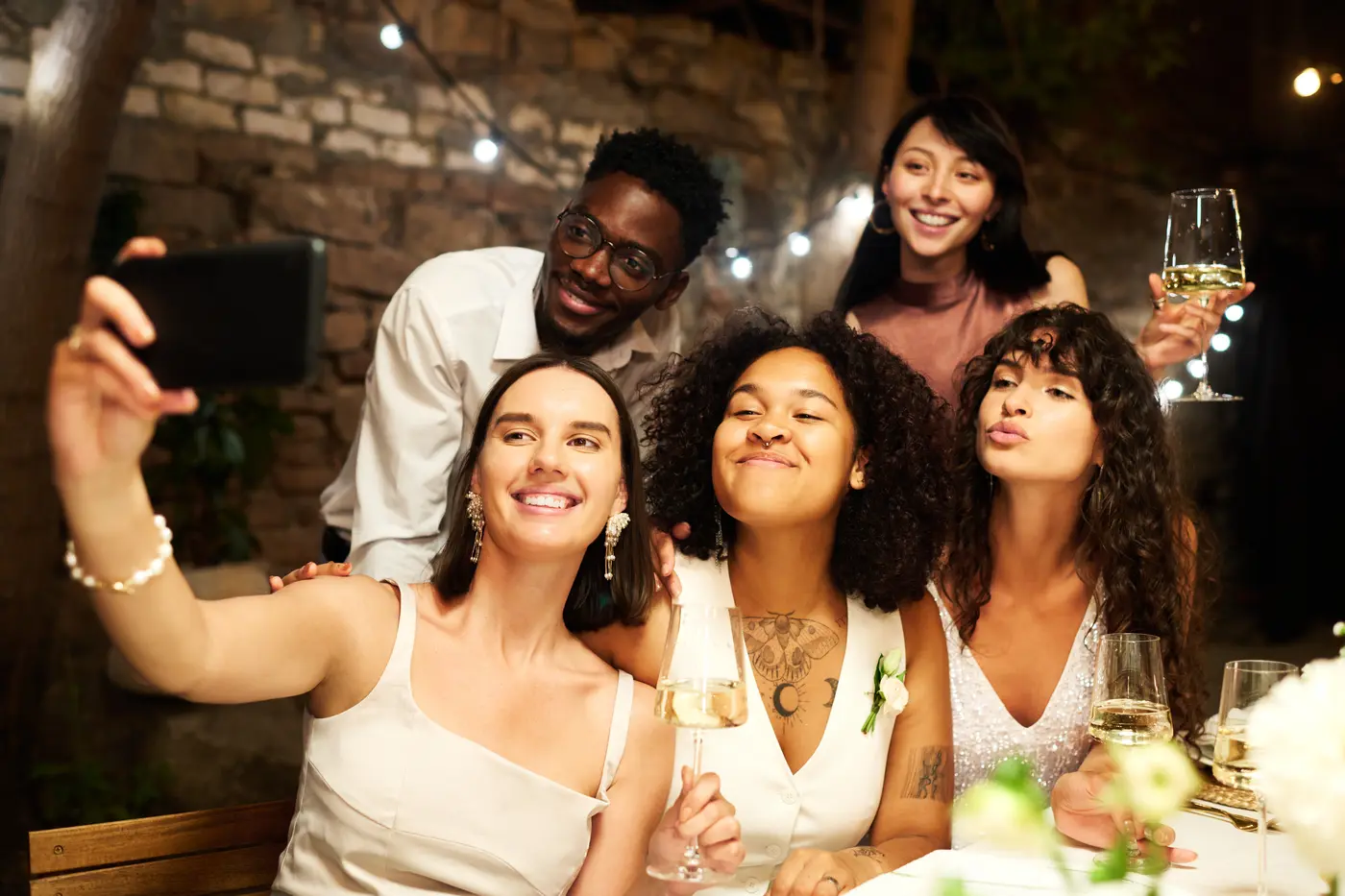 Gäste einer festlichen Abendveranstaltung machen gemeinsam ein Selfie am Tisch